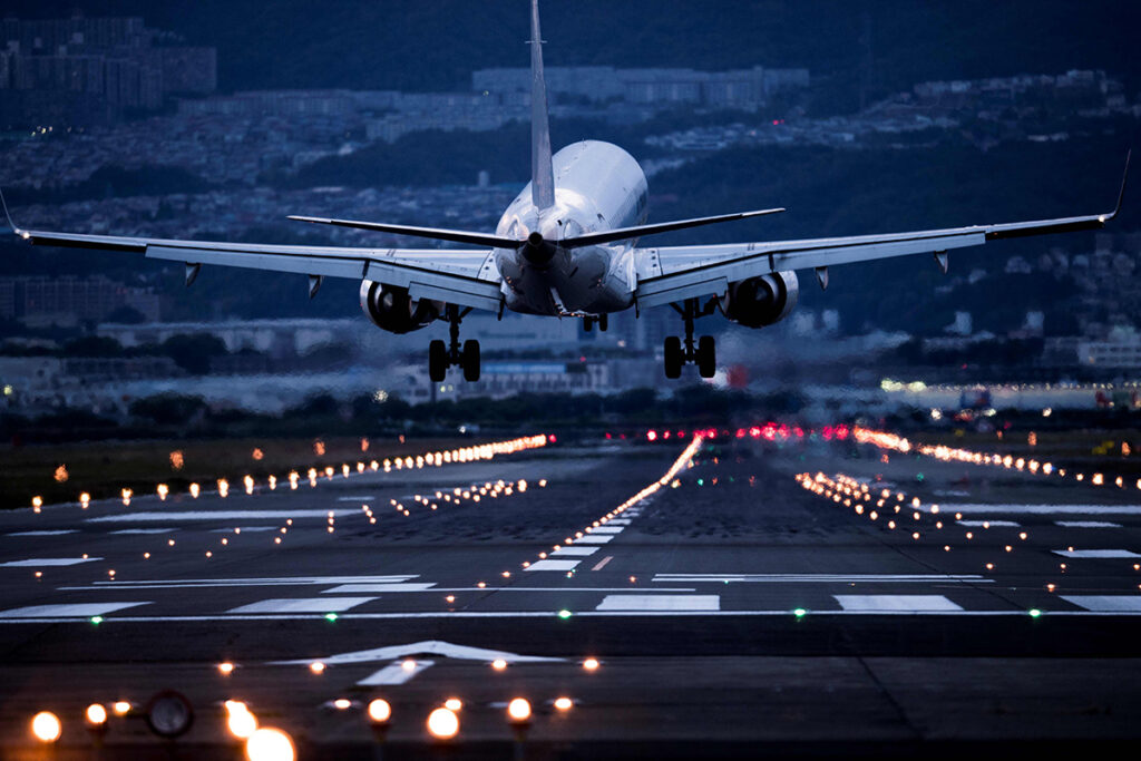 A plane takes off from a runway as dusk turns into night.